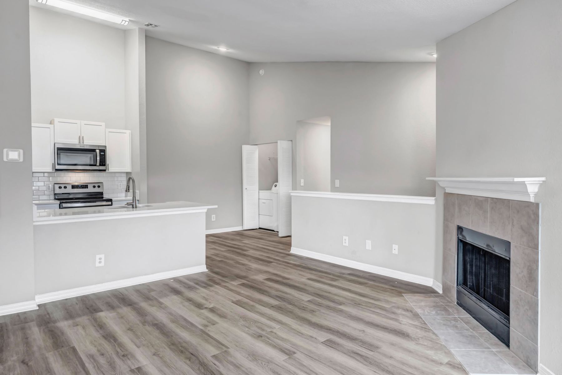 Empty room with wood floors, ceiling fan, and sliding glass door leading to a patio with vertical blinds at Apex West Midown.